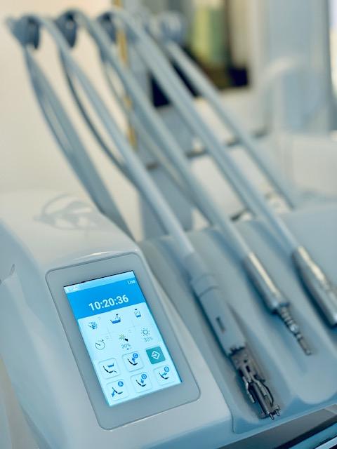 Billede af en moderne tandlægebehandling med digitale skærme og flere instrumenter til tandpleje.