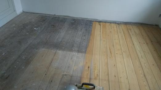 Gulvrenovering med en del af det gamle, slidte gulv og en ny, lys træbelægning.