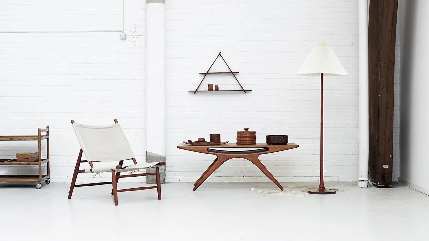 Moderne stue med en trælampe, et lavt bord, en stol og væghylder i minimalistisk design.