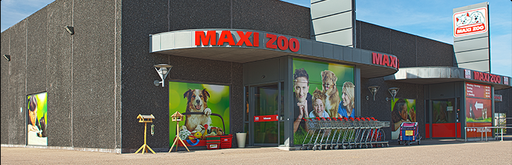 Maxi Zoo butik med farverige vægmalerier af hunde og børn, indkøbsvogne foran indgangen.