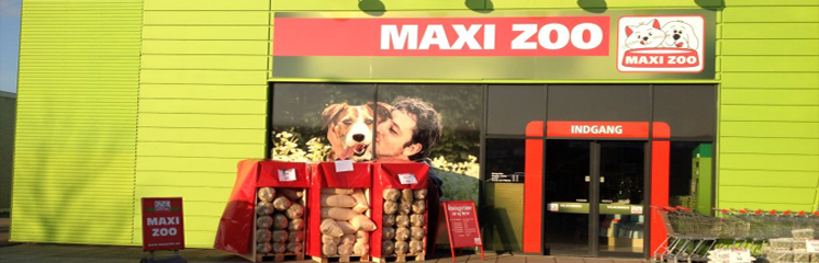 Maxi Zoo butik med hund og ejer ved indgangen, fyldt med hundefoder og tilbehør.