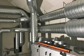 Ventilationssystem med metalrør og en arbejdsflade i et rum.