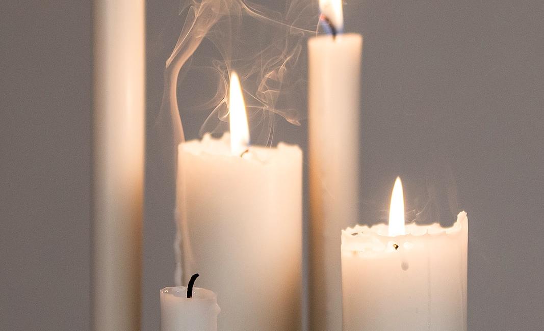 Flere hvide stearinlys med flammer og røg, der skaber en hyggelig atmosfære.
