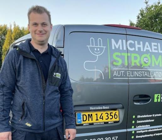 En mand står ved siden af en varevogn med teksten "Michael Strøm" og kontaktinformationer.