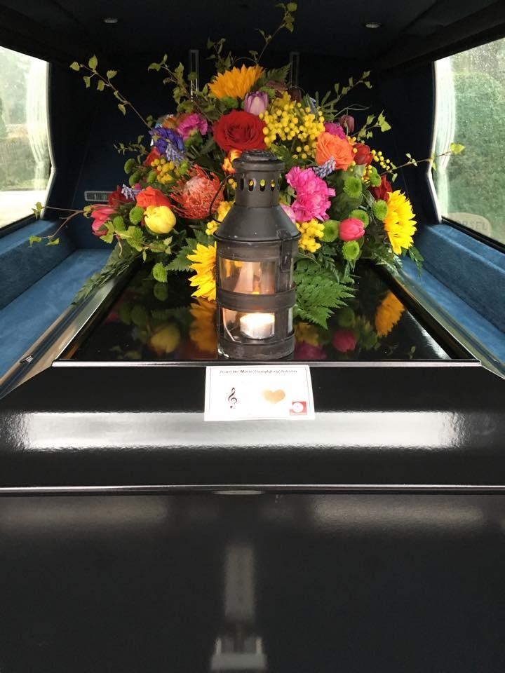 En kiste med en smuk blomsterkrans og en lampe, der står på en sort overflade i en limousine.