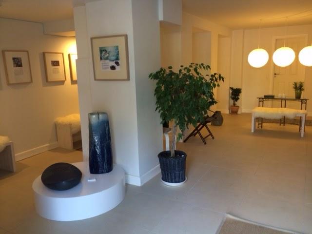 Lyst og moderne indendørsrum med planter, kunstværker og møbler i en afslappet atmosfære.