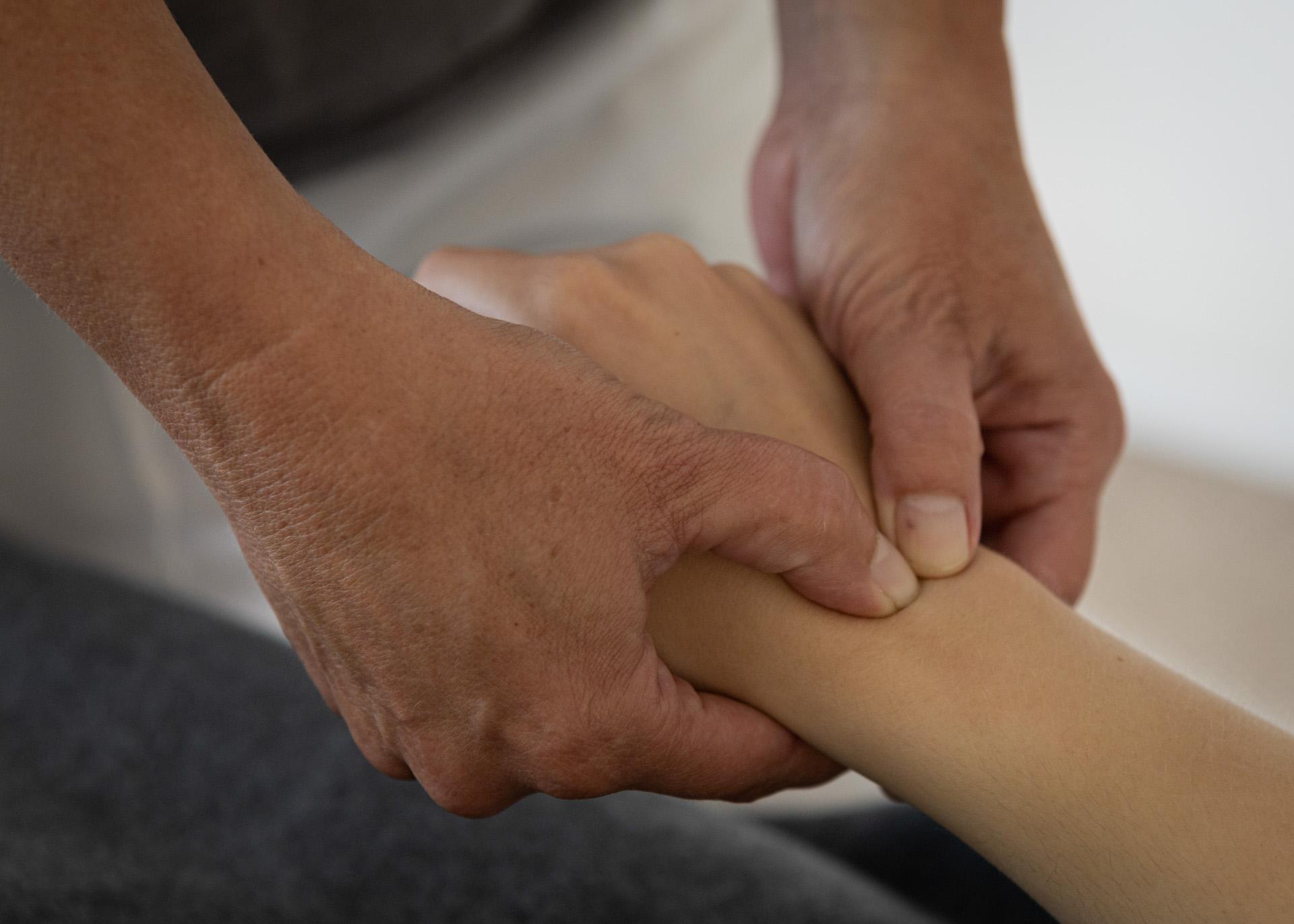 Hænder udfører en massage på en arm, der viser afslapning og velvære i en terapeutisk setting.