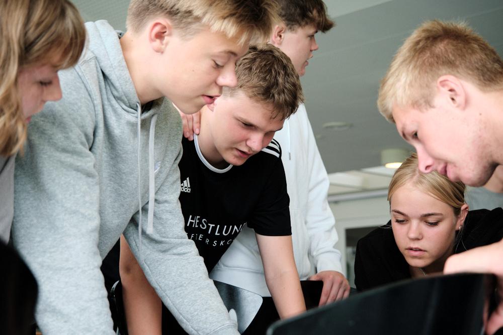 Gruppe af unge mennesker, der arbejder sammen om et projekt i et klasseværelse.
