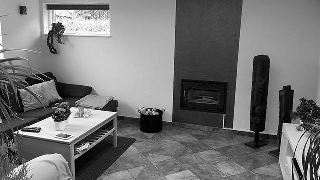 Stue med sofa, kaffebord, pejs og moderne dekorationer på væggene. Fliser på gulvet og planter i hjørnerne.