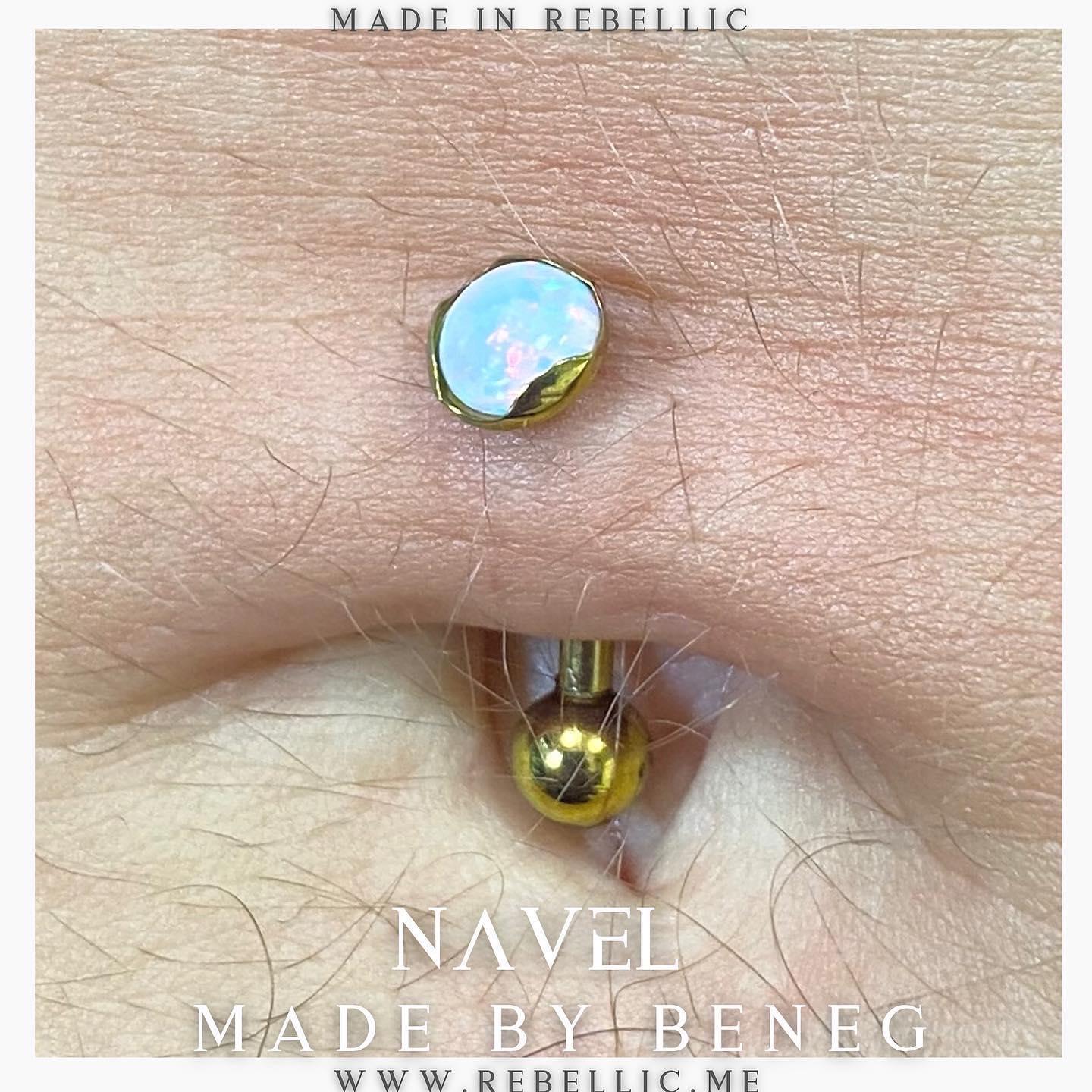 Navelpiercing med en glitrende sten og en gylden kugle, tæt på huden.