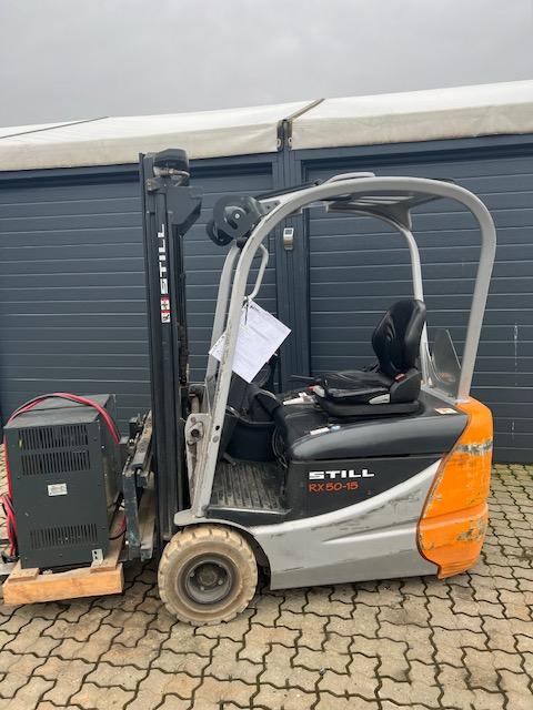 En stillads truck parkeret foran en garage med dokumenter på sædet og en elektrisk generator ved siden af.