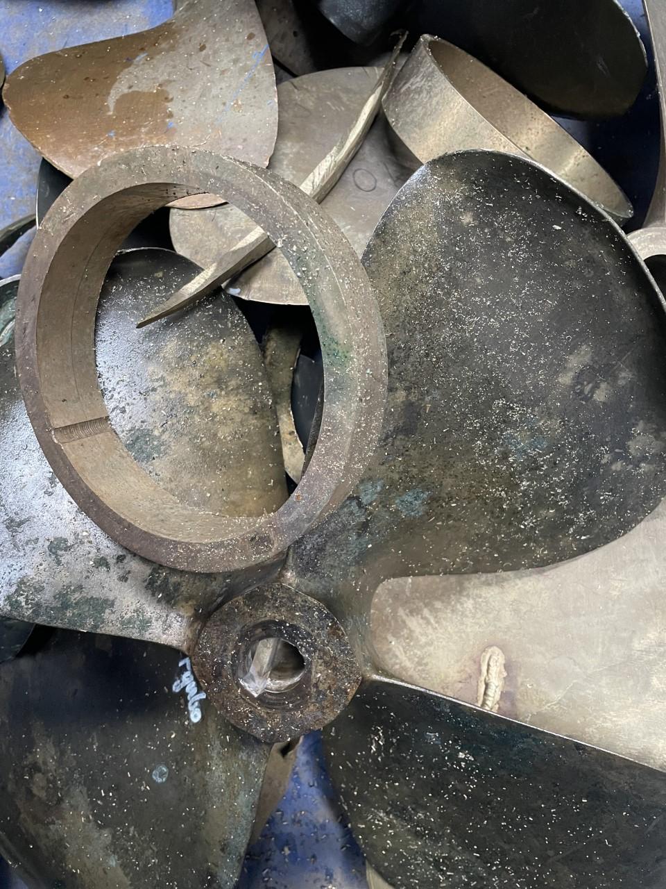 Bunker af metalpropeller og dele, der viser rust og slid på overfladen.