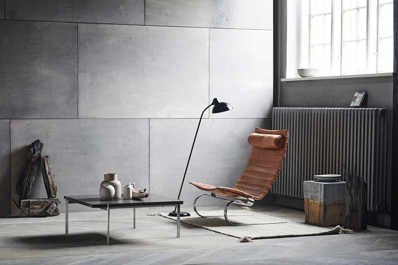 Moderne stue med en læderstol, et minimalistisk bord og dekorative genstande på en grå væg.