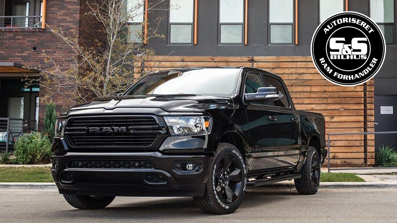 En sort pickup truck fra RAM parkeret foran en moderne bygning med store vinduer.