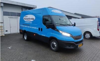 Blå varevogn med logo parkeret foran en bygning, ideel til transport og levering af varer.