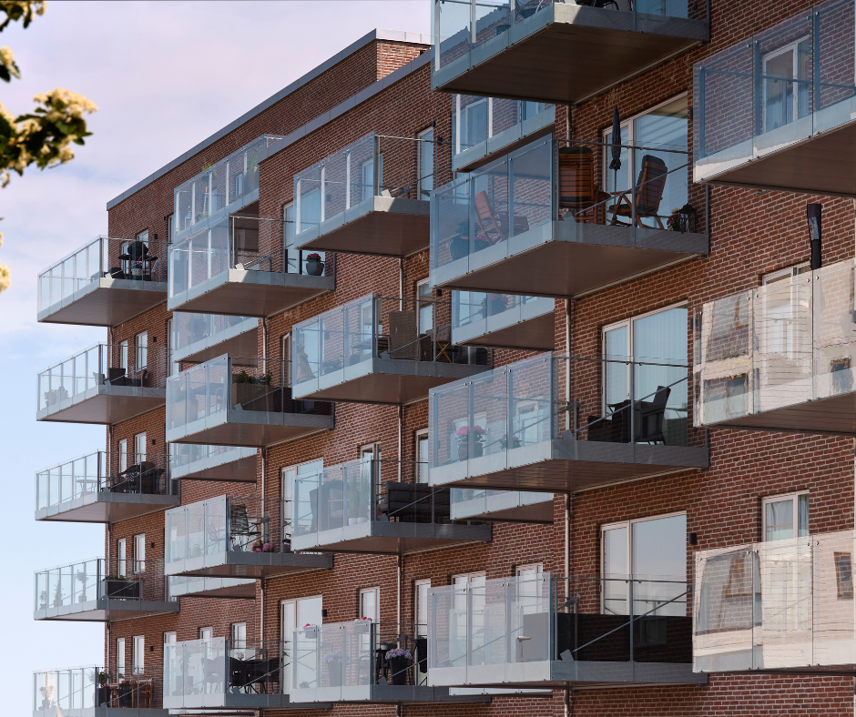 Moderne lejlighedsbygning med glasaltaner og murstensfacade.