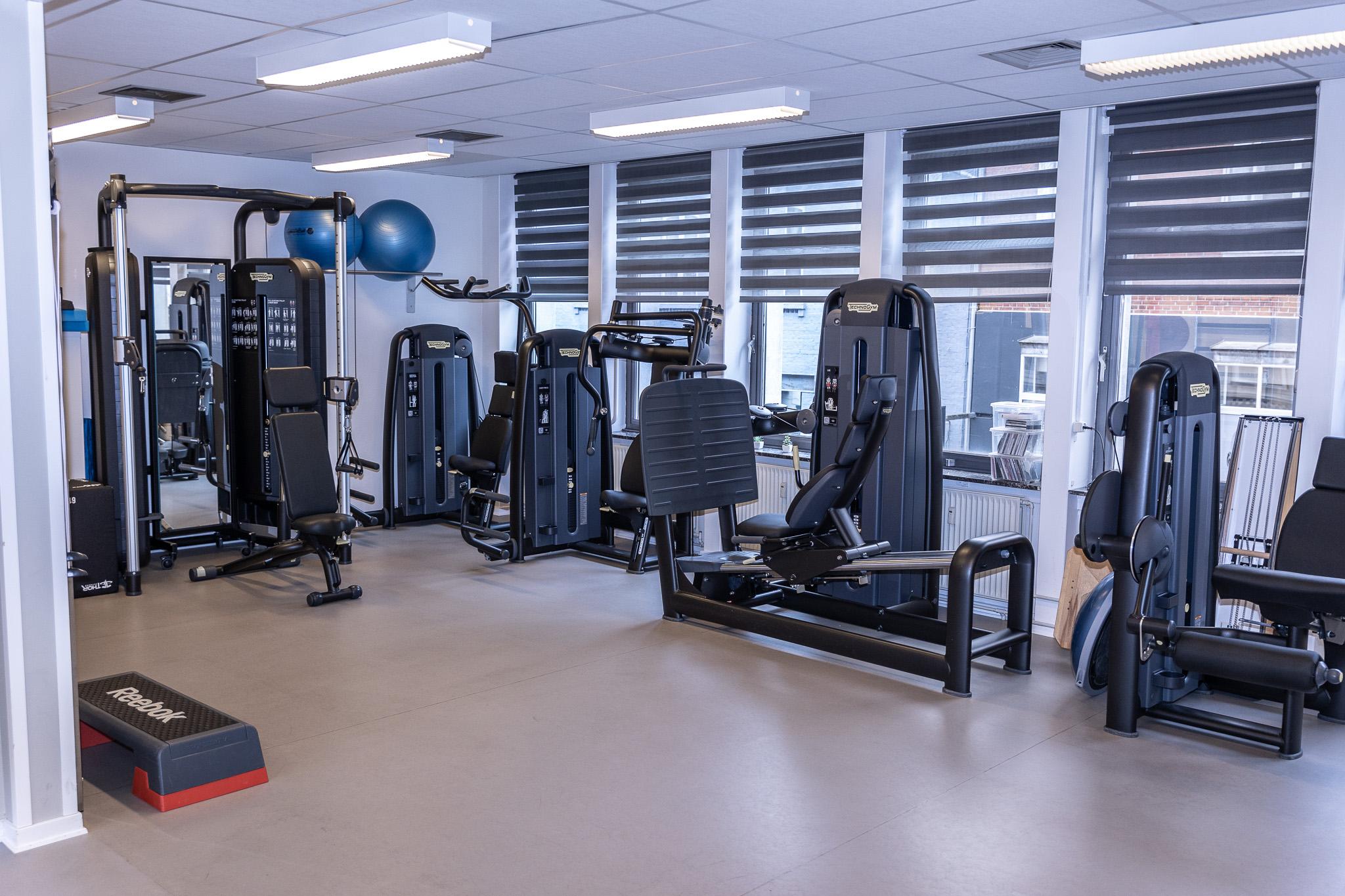 Træningslokale med fitnessudstyr som vægtmaskiner, konditionsmaskiner og træningsbolde.