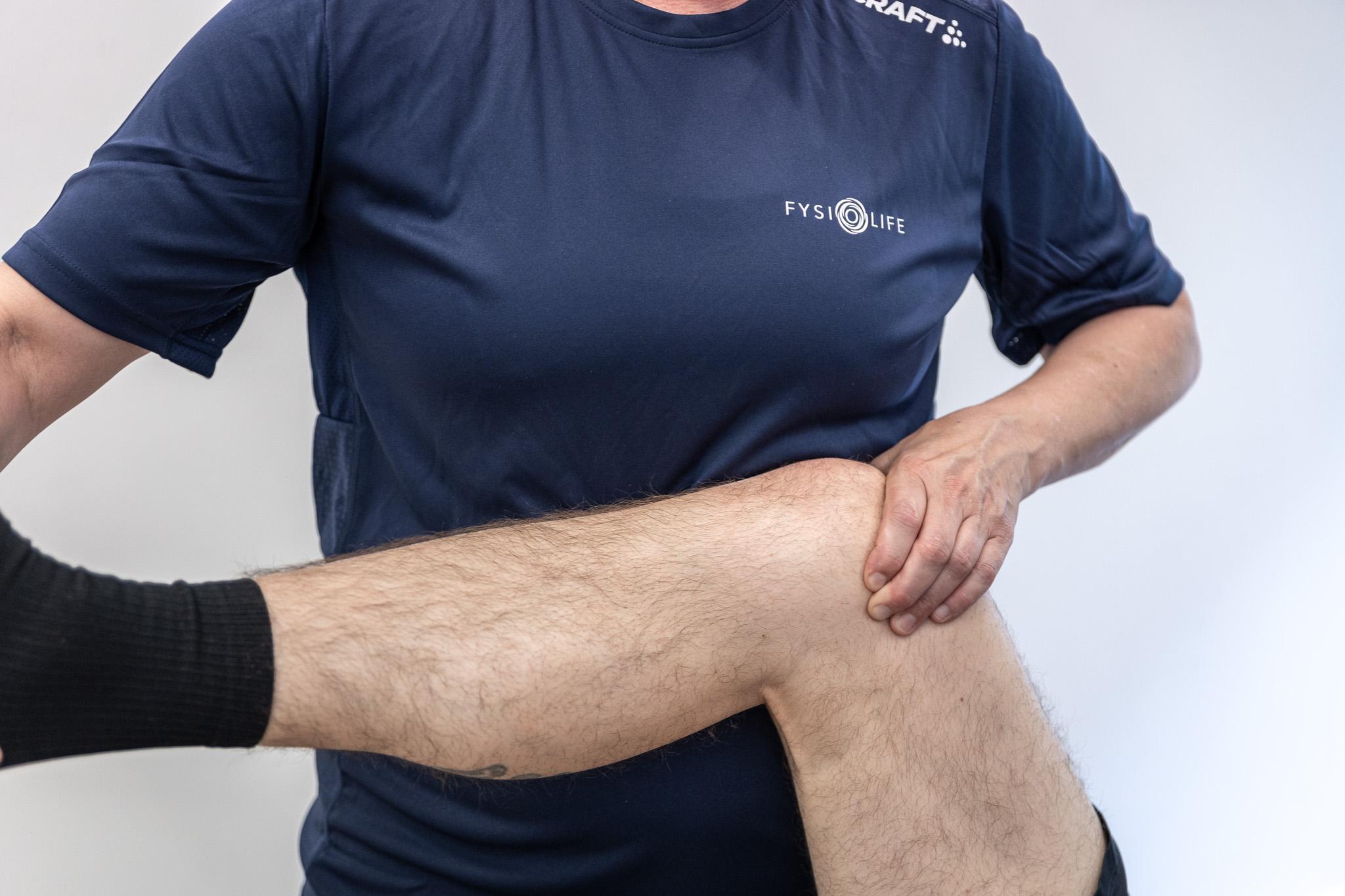 En person i en blå t-shirt strækker benet, mens de holder om knæet.