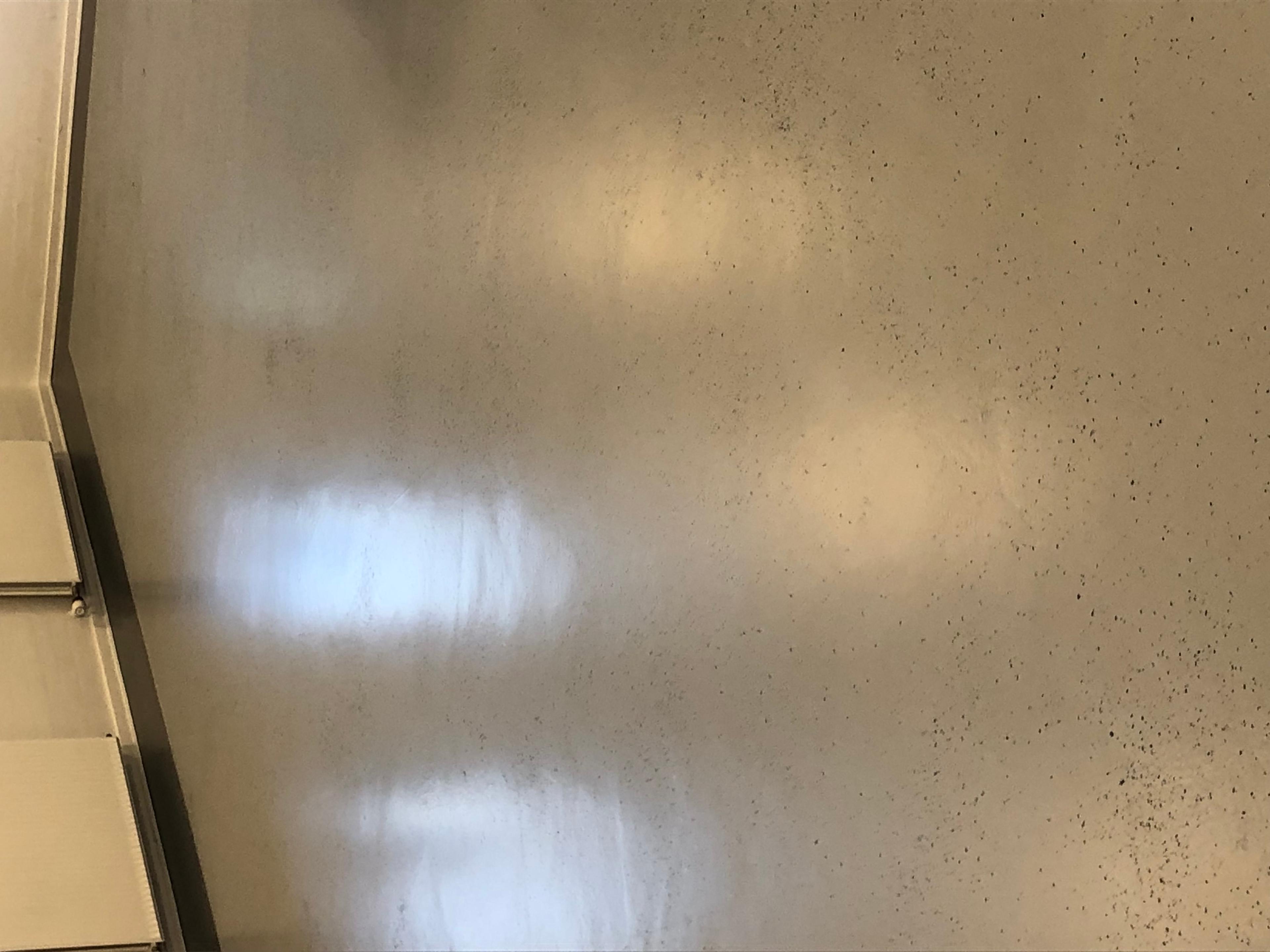 Et glat, gråt gulv med reflekterende overflade i et lyst rum.