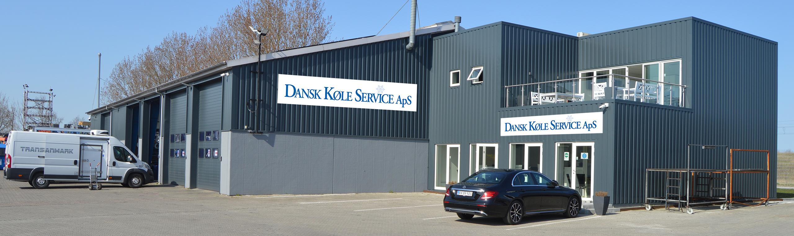 En moderne bygning med grå facade og store vinduer, der huser en virksomhed med navnet "Diverse Yacht Service".