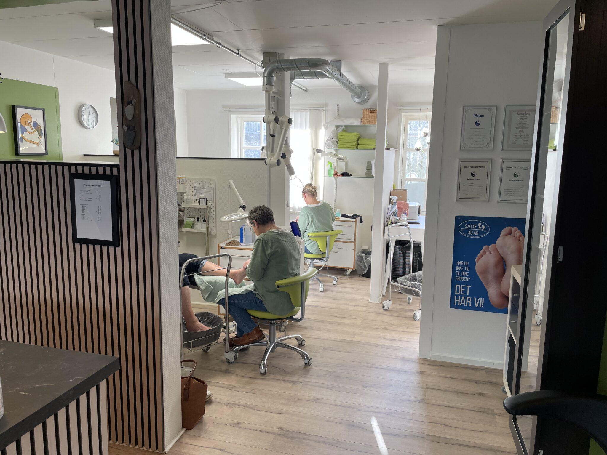 En moderne tandklinik med patienter i behandlingsstole og tandlæger, der arbejder i et lyst og åbent rum.