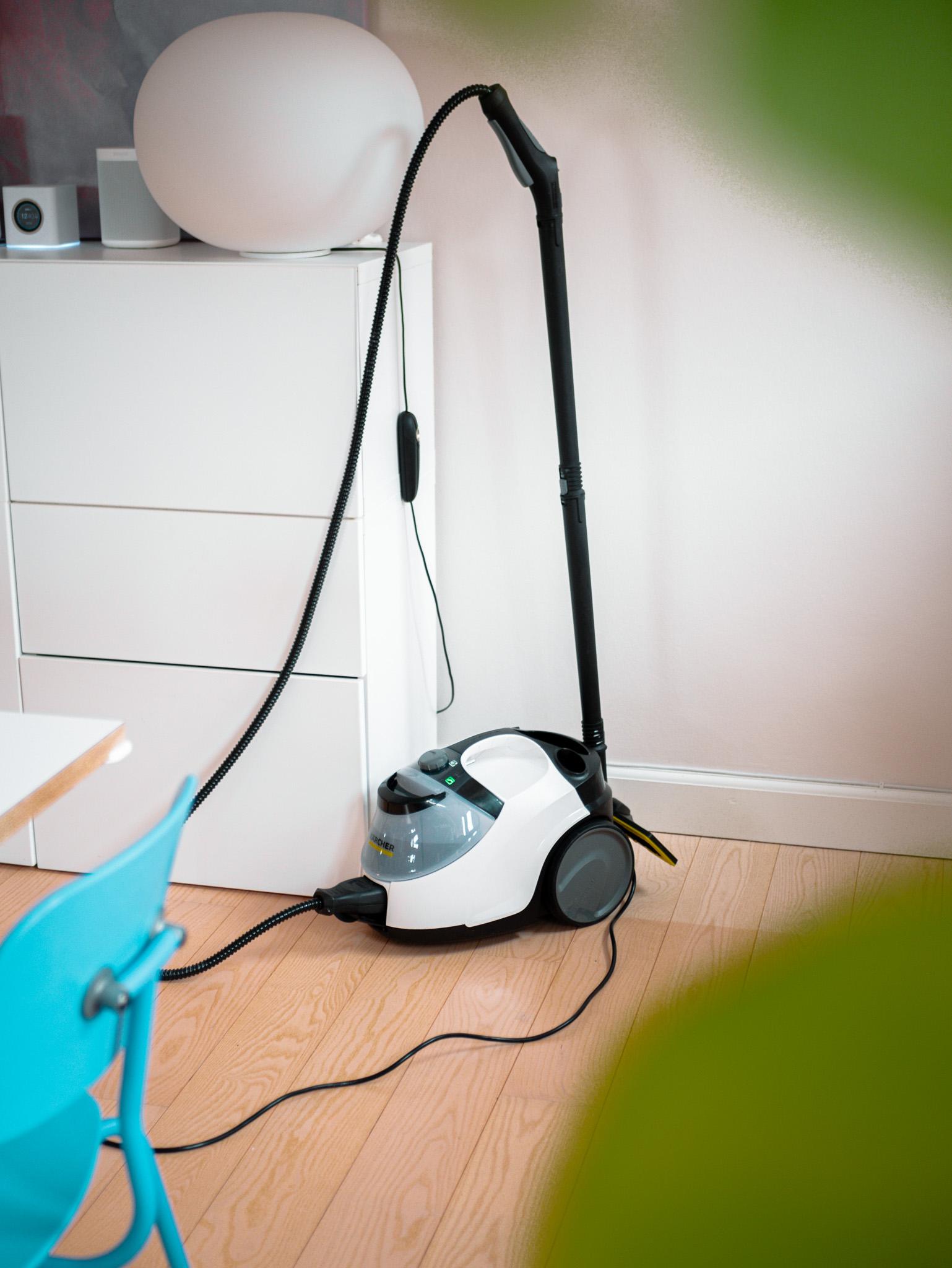 En støvsuger står på gulvet ved en hvid kommode i et lyst rum med grønne planter i forgrunden.