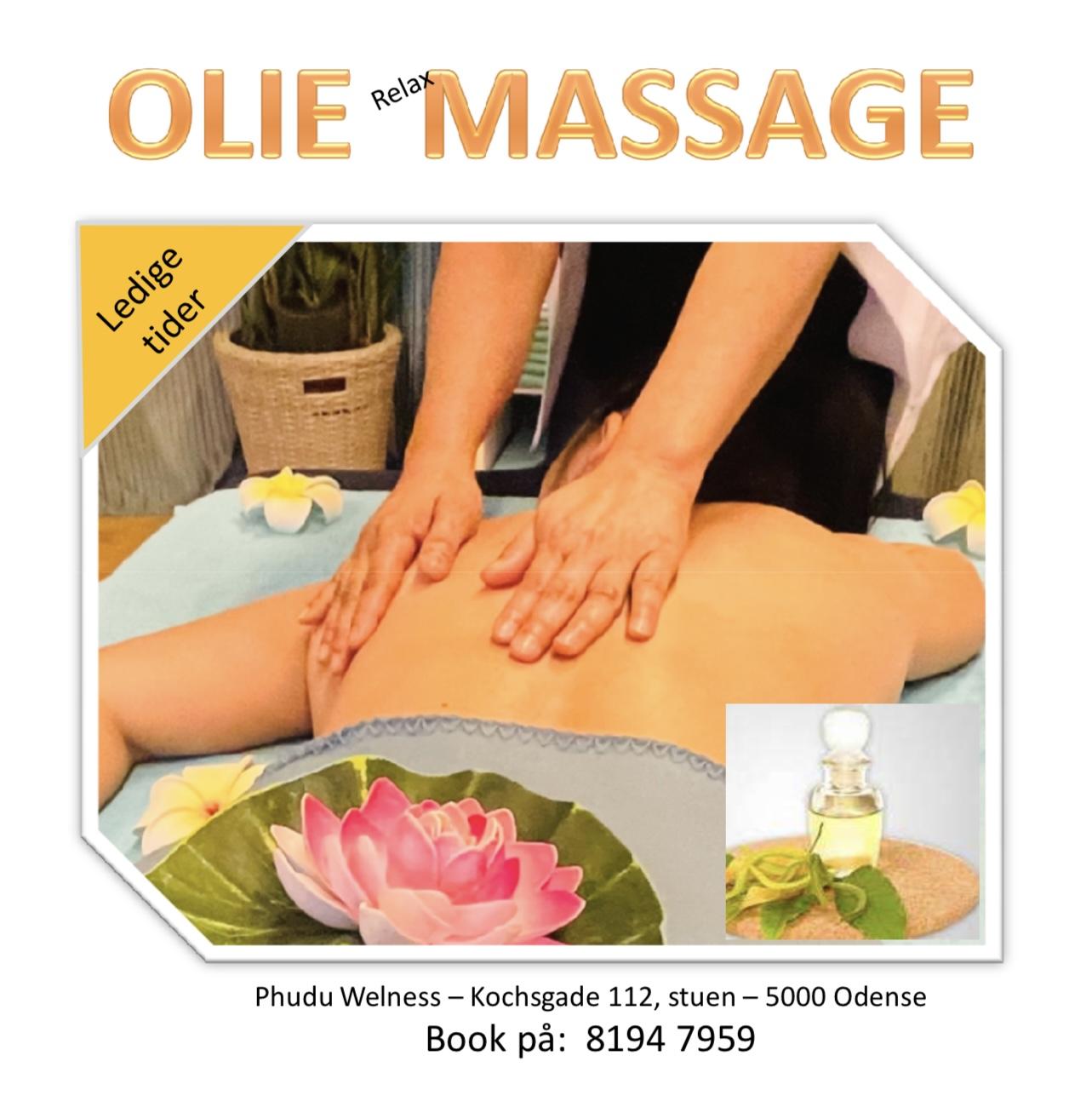 En person får olie massage på en massagebriks med en lotusblomst og massageolie i baggrunden.