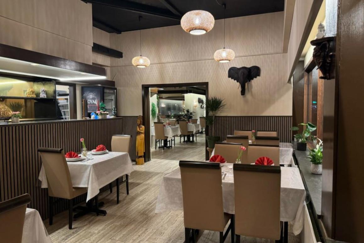 Elegant restaurantindretning med hvide duge, stole og belysning, der skaber en hyggelig atmosfære.
