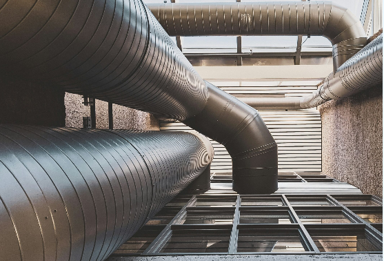 Billede af metalrør, der strækker sig opad i en moderne bygning med glasvægge og industrielt design.