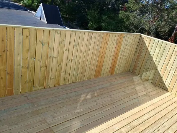 En ny træterrasse med en trævæg, der giver en moderne og naturlig atmosfære i haven.