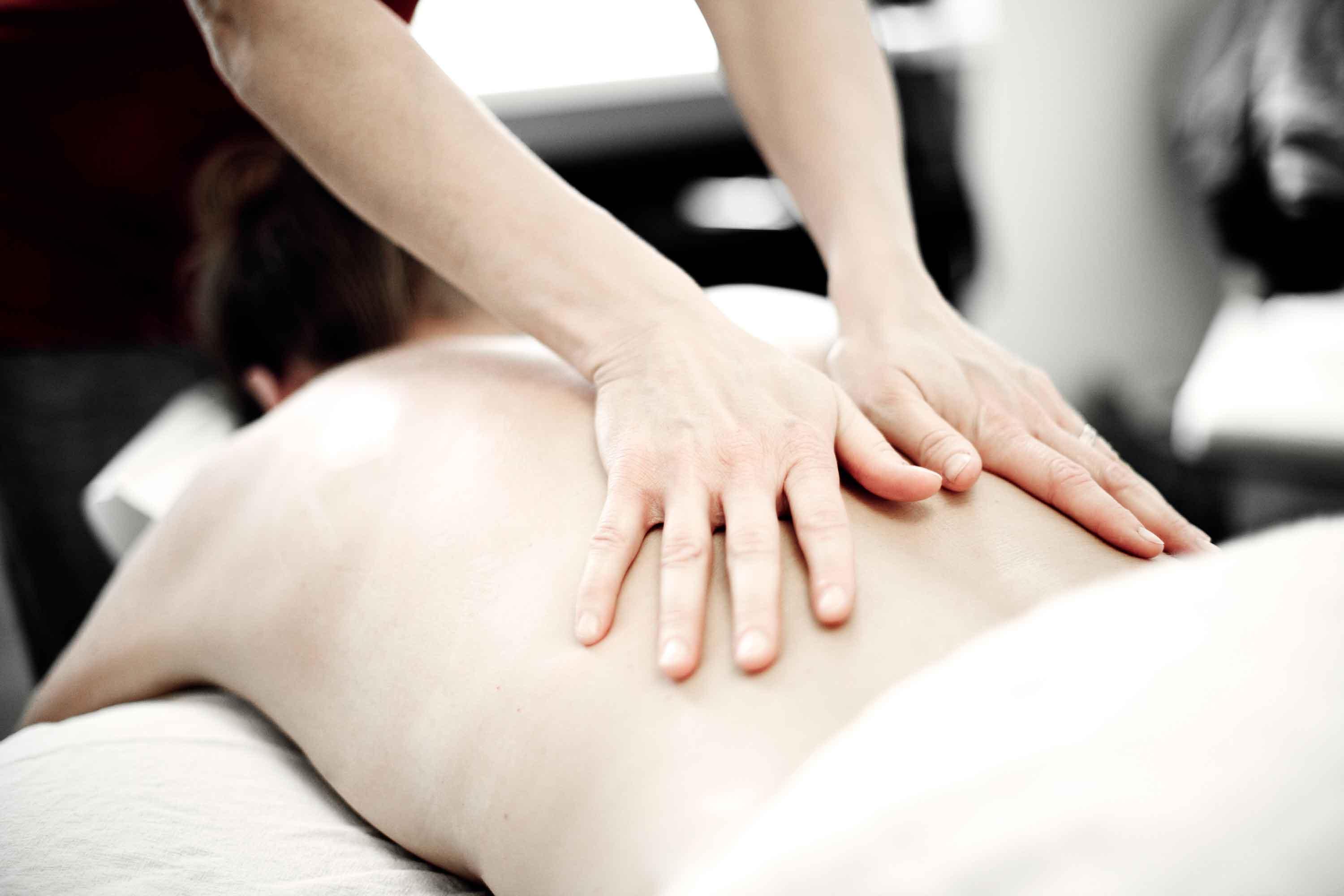 En person får en rygmassage med hænderne i en klinisk indstilling.