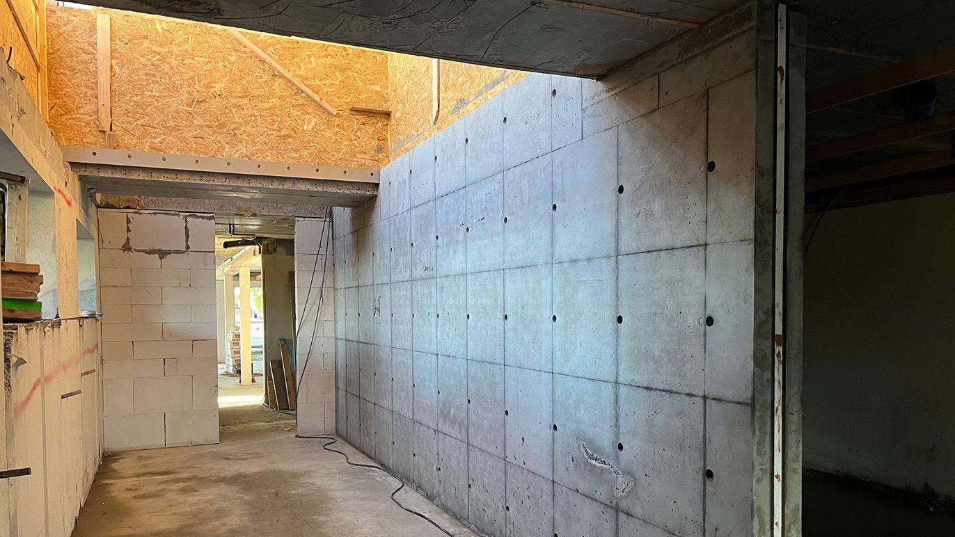Indvendig udsigt af en bygning med betonvægge og åbent rum, der viser byggearbejde og materialer.