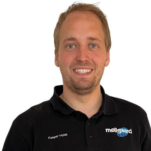 En smilende mand iført en sort polo med logoet fra Møllgaard, står foran en hvid baggrund.