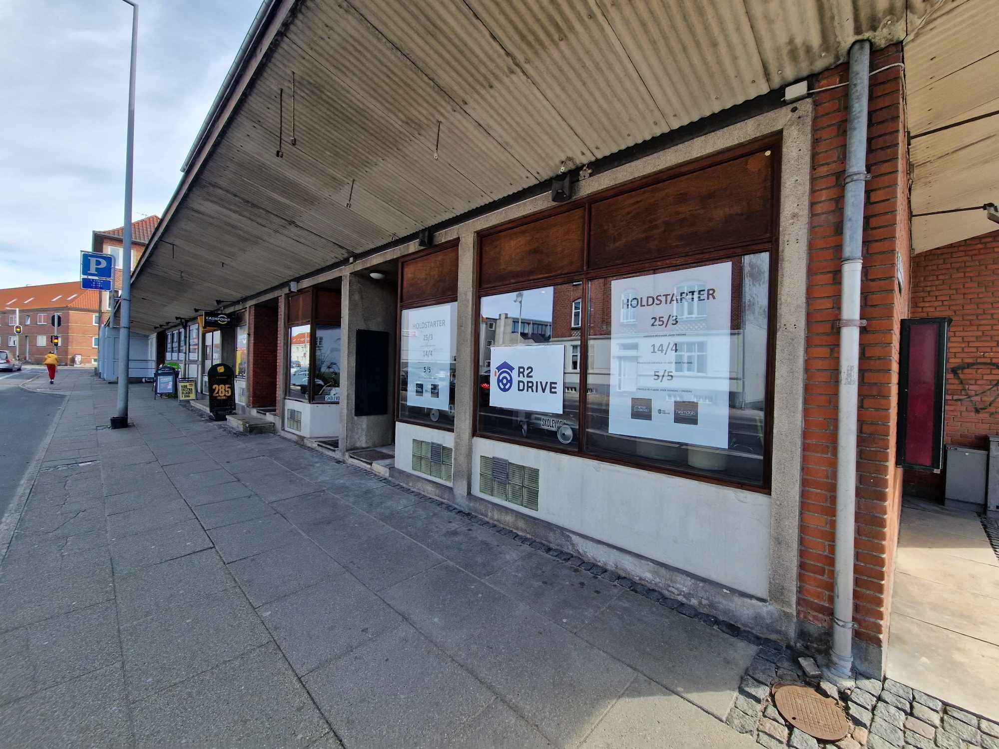 Facade af en bygning med vinduer og skilte, der annoncerer auktioner, beliggende på en gade.
