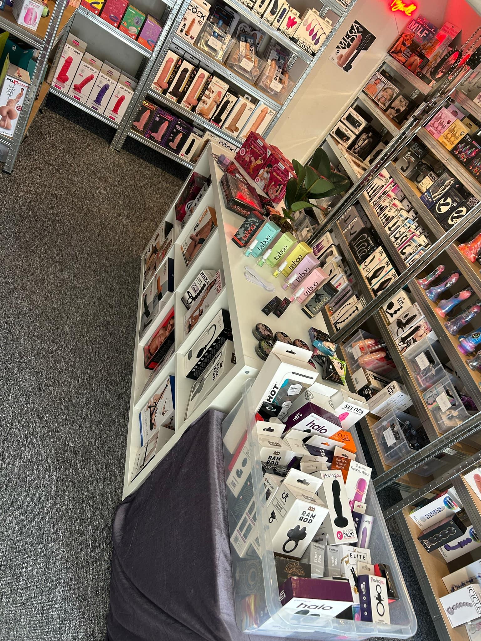 En butik med sexlegetøj, hvor der er en hvid disk og en kurv fyldt med forskellige produkter.