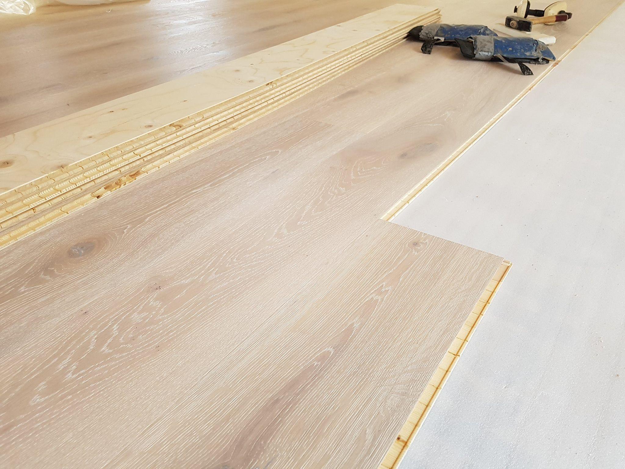 Billede af et gulv med laminatplanker, der bliver installeret med værktøj i baggrunden.