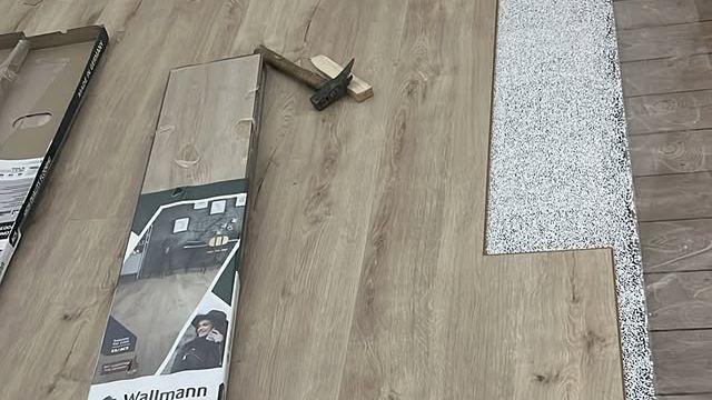 Billede af laminatgulvplader og værktøj til installation af gulvbelægning på en overflade.
