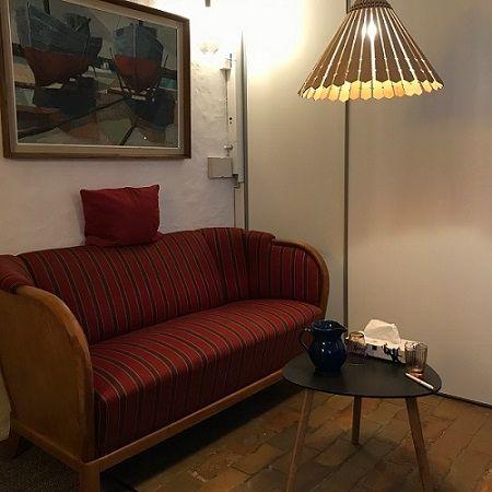 En hyggelig stue med en rødstribet sofa, et lille bord og en lampe, der hænger over bordet.
