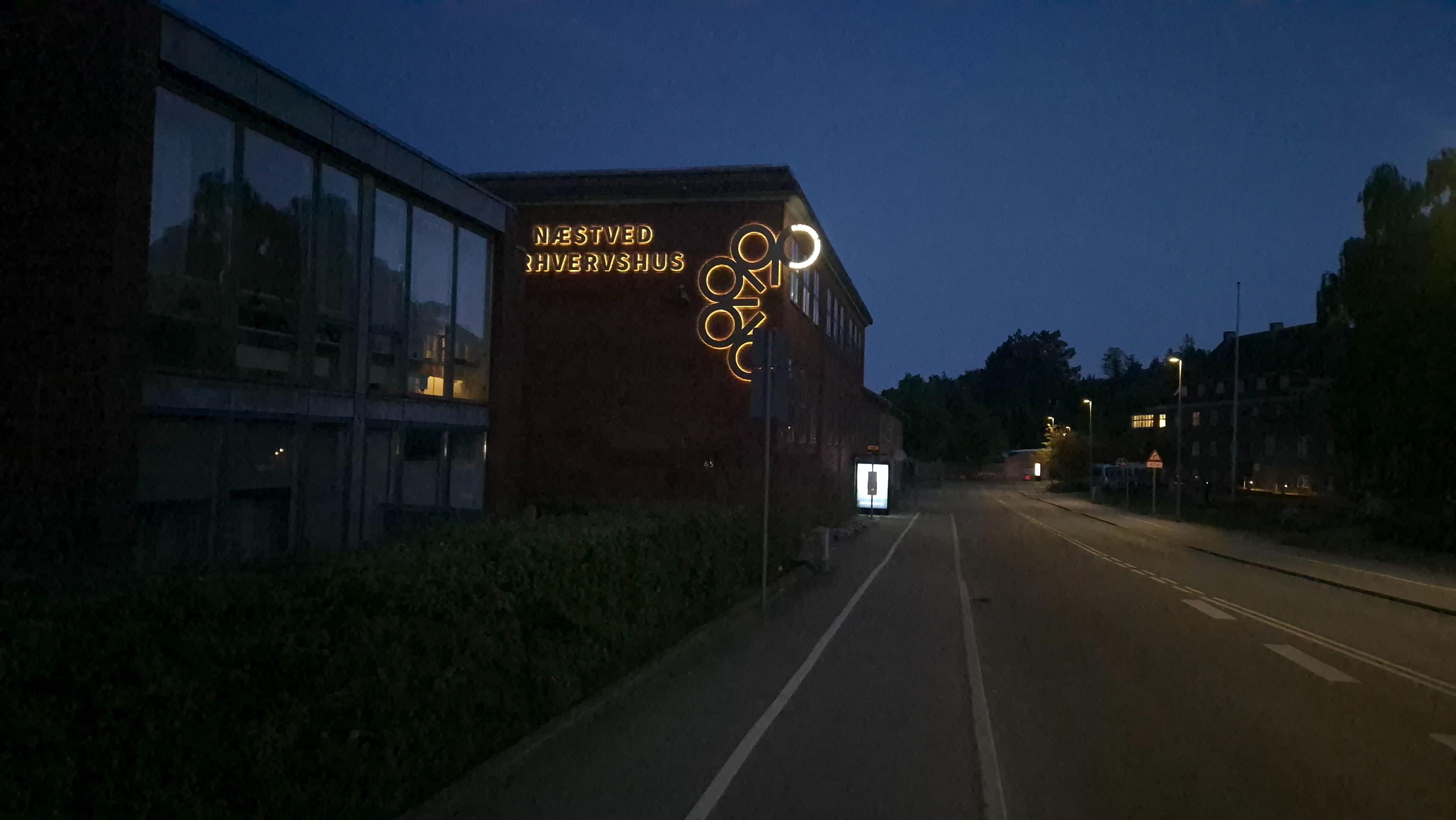 Bygningen med lysende skilt "Sankt Hans Hospital" ved vejen om aftenen.