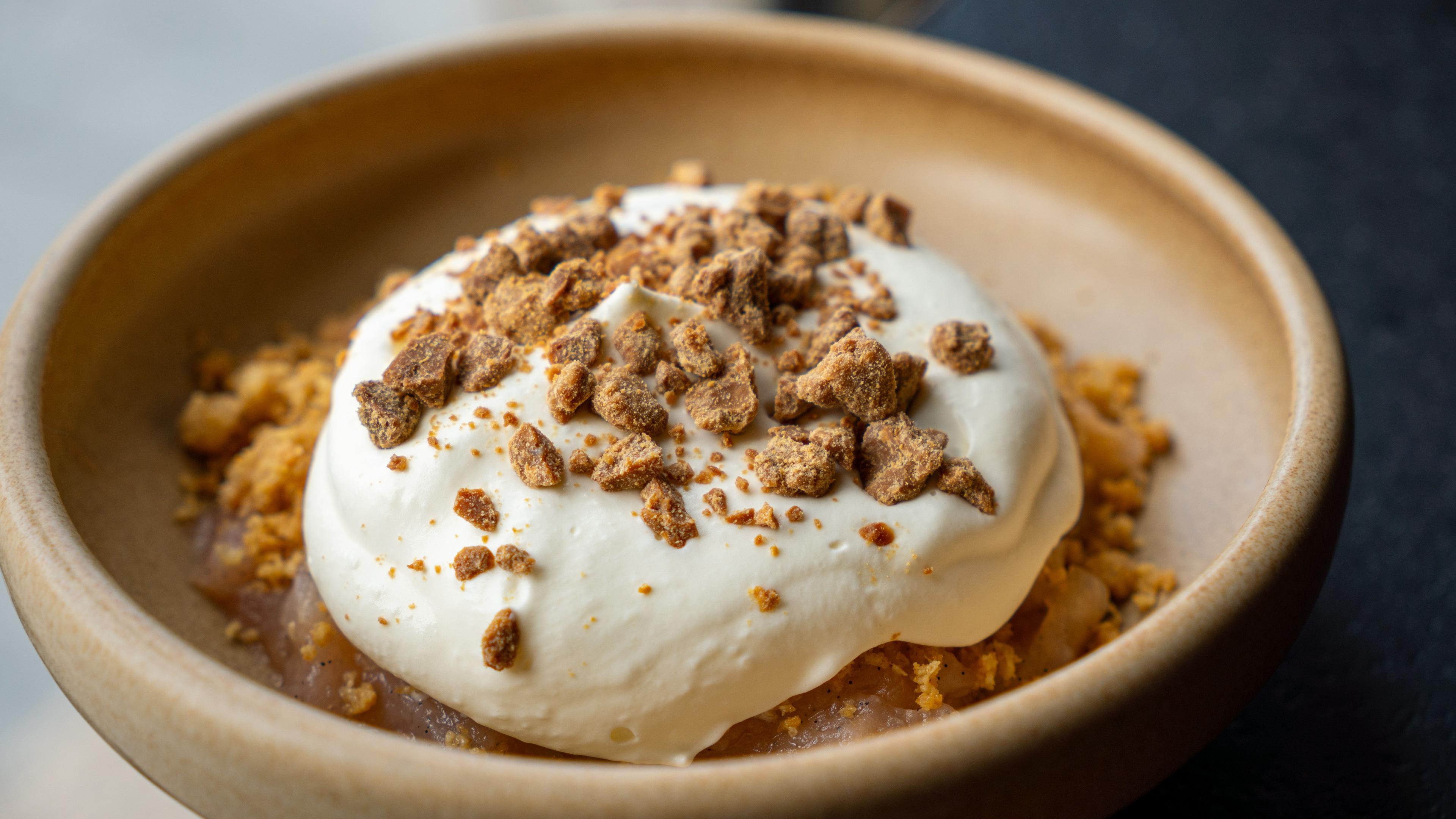 En skål med dessert bestående af knuste småkager, flødeskum og en sprød bund.