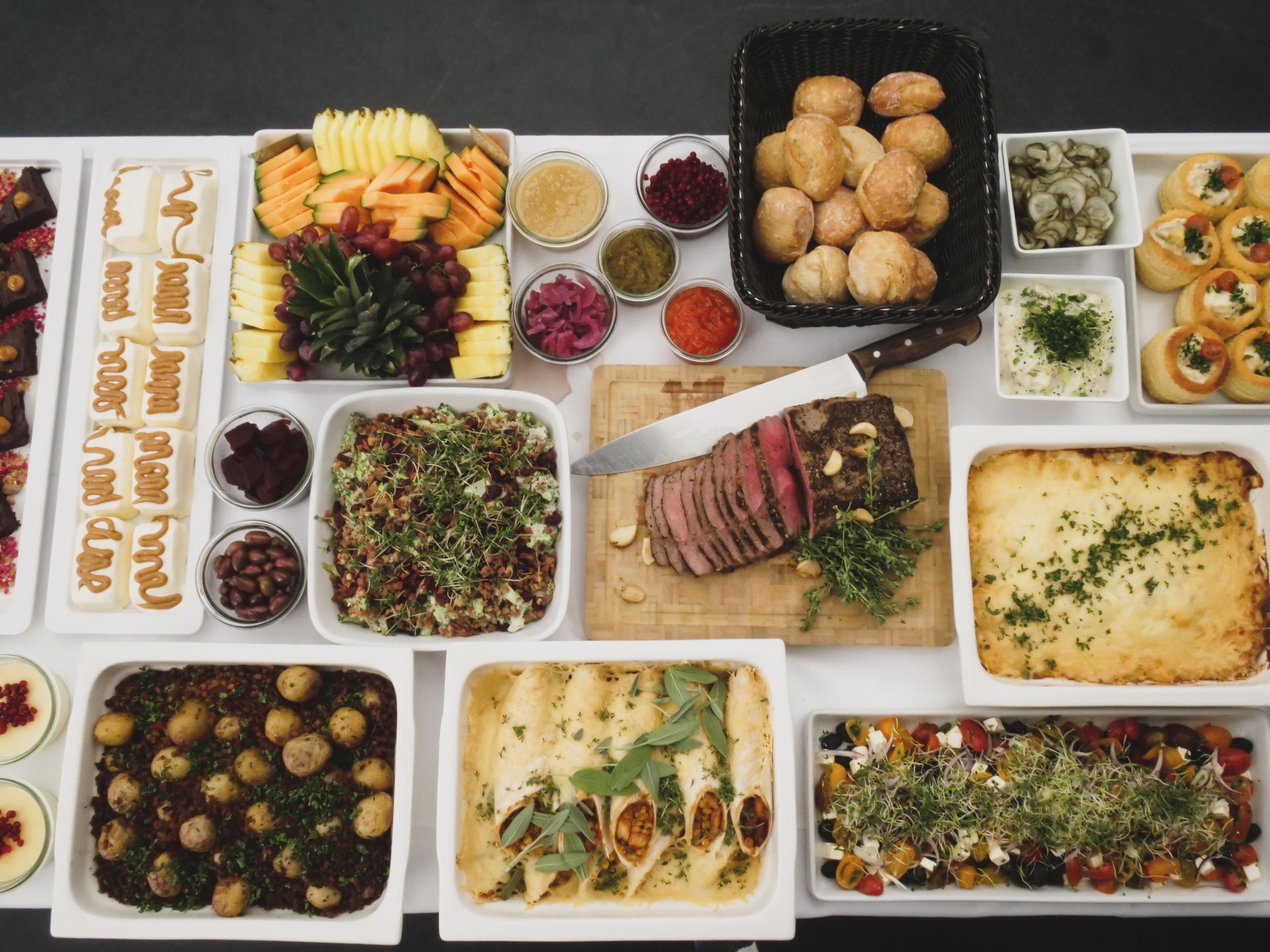 Et festligt bord dækket med forskellige retter, herunder kød, grøntsager, brød og desserter.