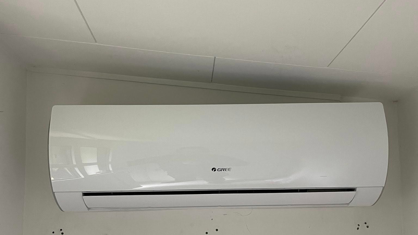 Vægmonteret airconditionanlæg i hvidt design, installeret i et rum med lys væg.
