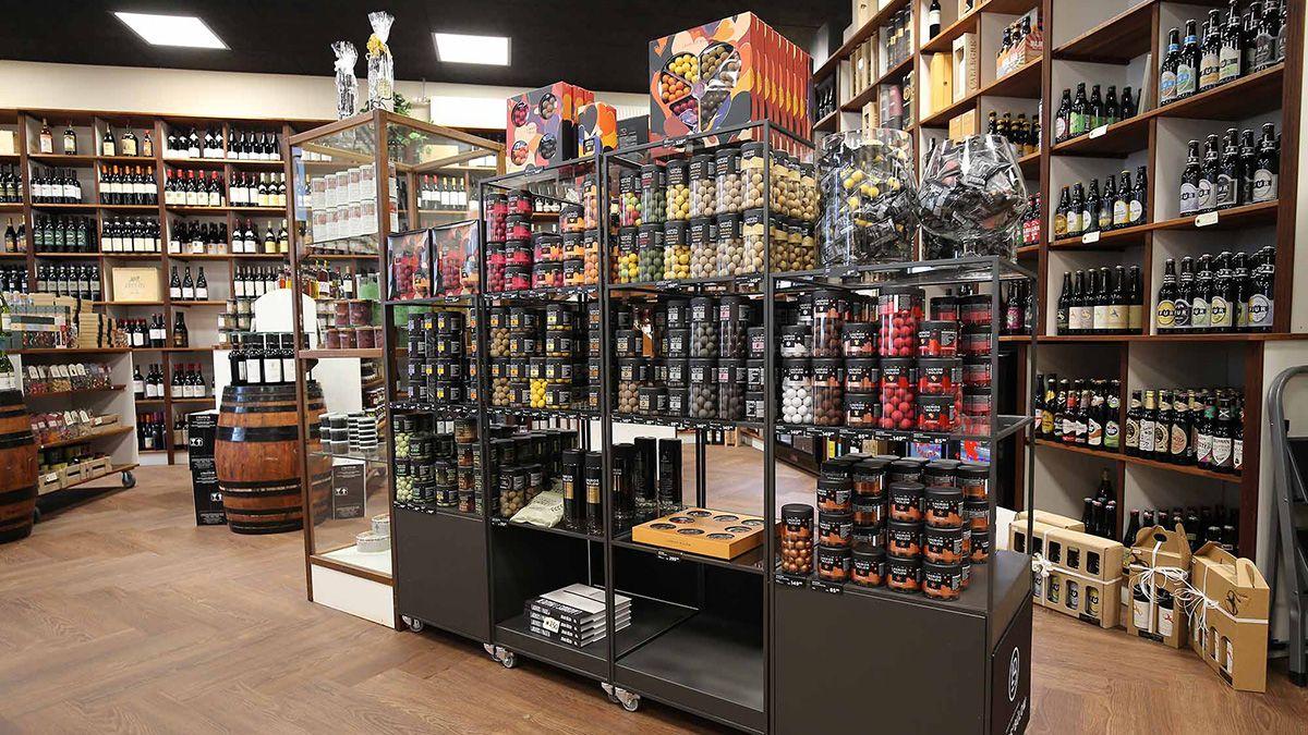 En indendørs butik med hylder fyldt med flasker og glasbeholdere, der tilbyder forskellige specialiteter og delikatesser.