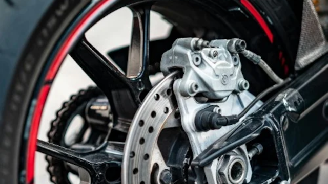 Bremsekaliber og hjulophæng på en motorcykel med detaljeret fokus på bremsesystemet.