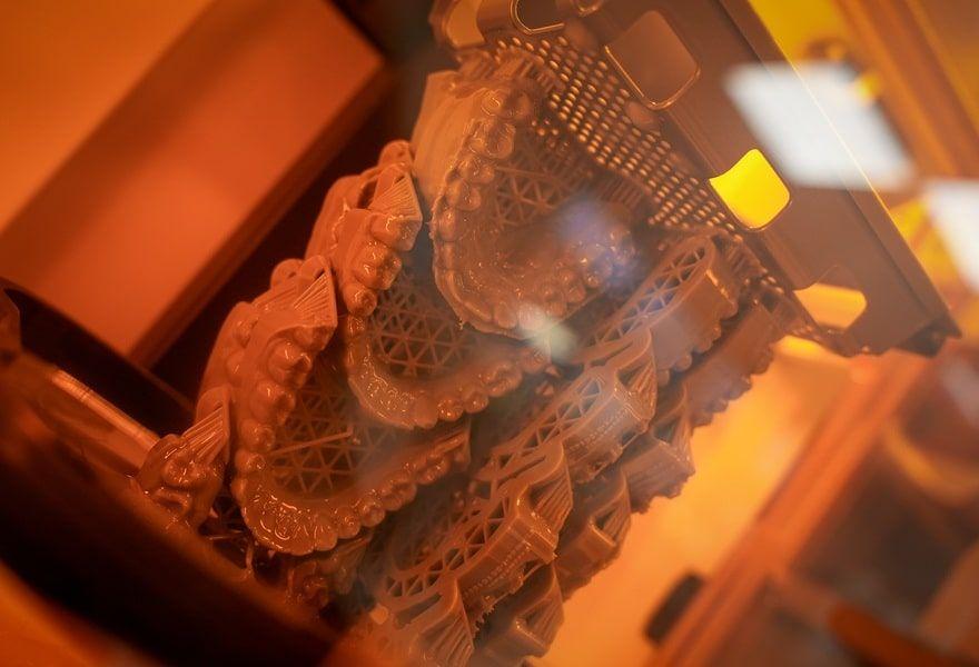 En detaljeret 3D-udskrift af en kompleks struktur i en udstillingsvitrine med orange belysning.