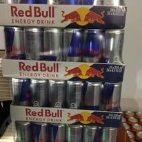En stak med Red Bull energidrikke i dåser, stablet på en hylde i en butik.