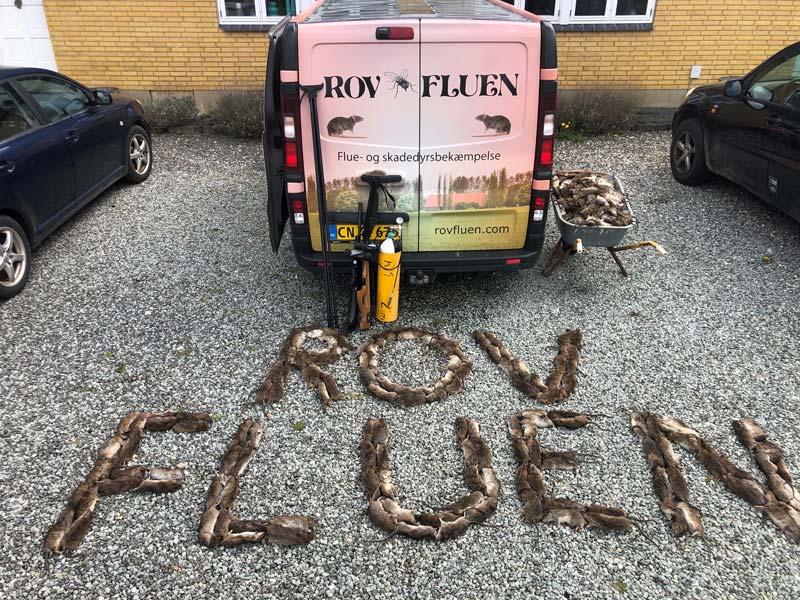 Billede af en trailer med teksten "ROVFLUEN" lavet af jaget vildt på grusbelægning.