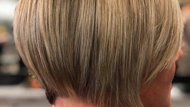 Kort, moderne frisyr med bløde lag og lys blond farve set fra siden.
