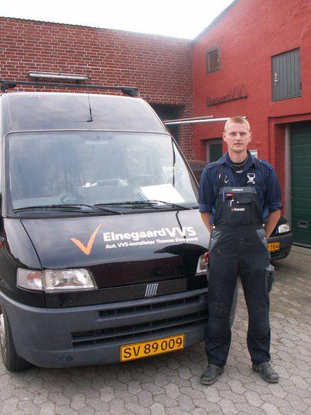 En mand står ved siden af en sort varevogn med logoet "ElnegardWS" på siden.
