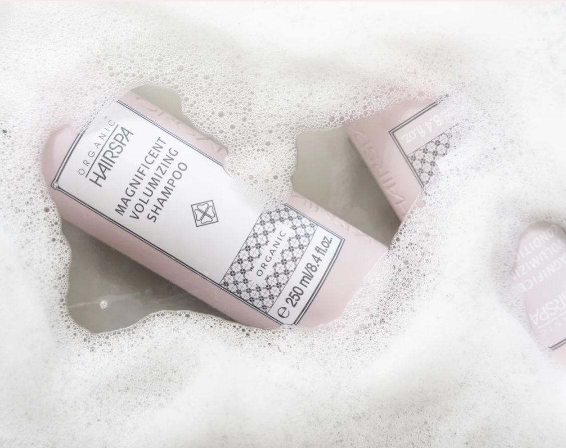 Hårprodukter i skum, herunder volumengivende shampoo i en lyserød flaske.
